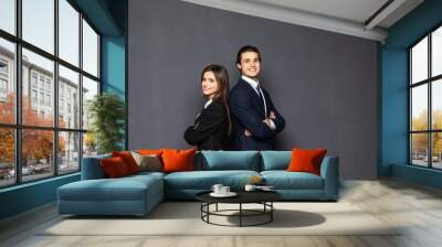 Business man and woman standing back to back isolated on gray background. Teamwork concept Wall mural